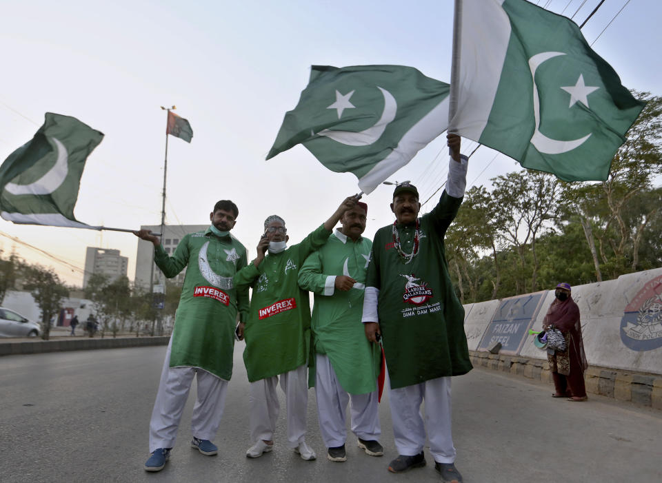 Cricket fans hold National flags while they arrive at the National Stadium to watch Pakistan Super League T20 cricket opening match between Karachi Kings and Quetta Gladiators at National Stadium, in Karachi, Pakistan, Saturday, Feb. 20 2021. Spectators returned to cricket stadiums in Pakistan for the first time since the coronavirus pandemic began when the sixth edition of the Pakistan Super League begins in the southern port city of Karachi. (AP Photo/Fareed Khan)