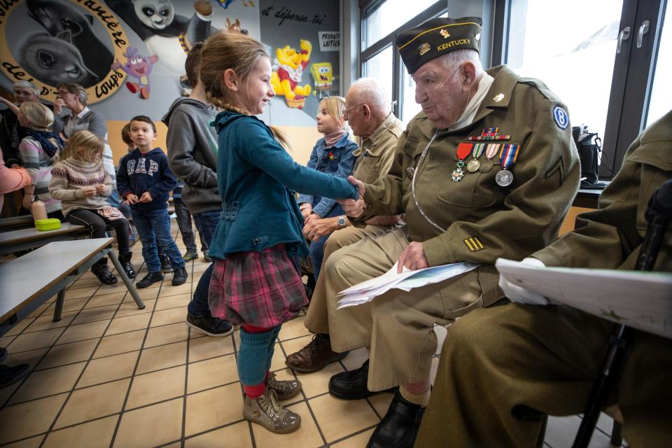 94 year-old George Merz, veteran of the Battle of the Bulge is greeted by a young student at the Noeville Belgium Public School. Dec. 13, 2019