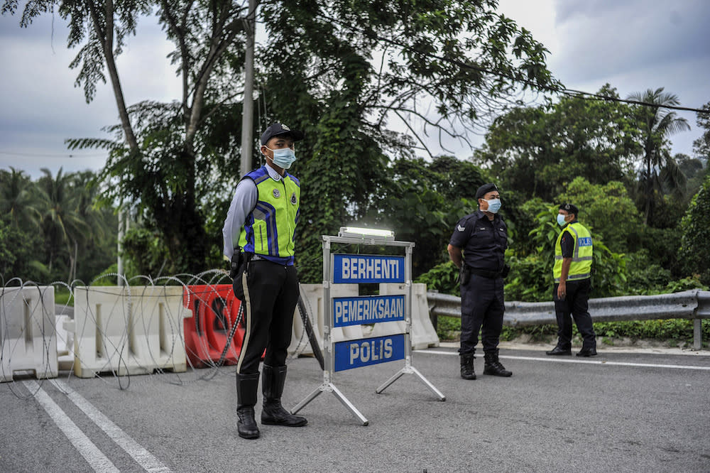 Police officers conducting checks at a roadblock during the enhanced movement control order (EMCO) in seven villages in Hulu Langat, March 30, 2020. — Picture by Shafwan Zaidon