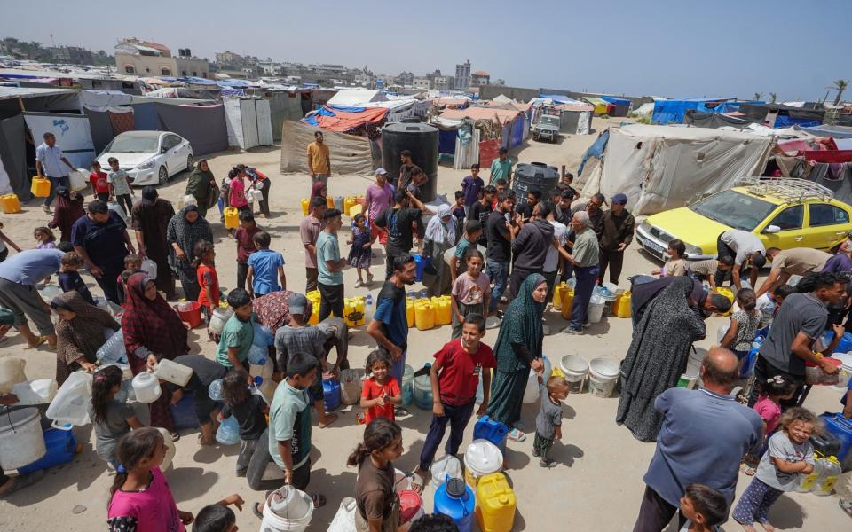 Displaced Palestinians queue for water at a camp west of Deir al-Balah in the Gaza Strip