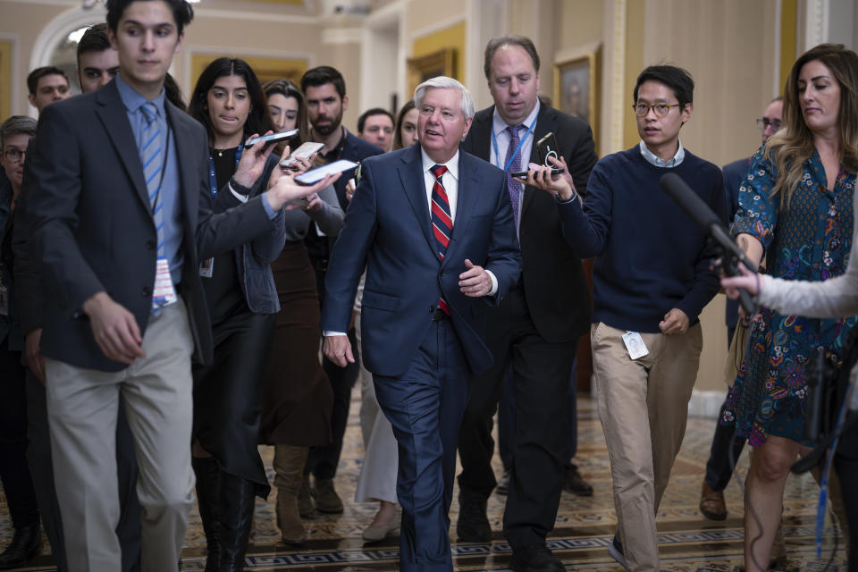 With reporters seeking comment, Sen. Lindsey Graham, R-S.C., walks to the chamber during a test vote to begin debate on a border security bill, at the Capitol in Washington, Wednesday, Feb. 7, 2024. (AP Photo/J. Scott Applewhite)