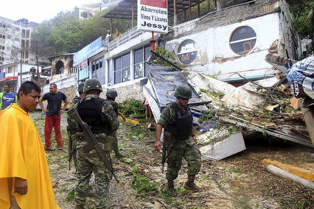 Soldiers and residents look at a restaurant damaged by a fallen tree and lamp post, caused by winds and rains brought by tropical storm Carlos in Acapulco, Mexico June 14, 2015. REUTERS/Claudio Vargas