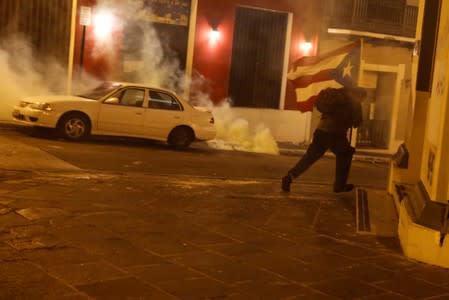 A demonstrator holding a Puerto Rican flag runs during clashes with the police in a protest calling for the resignation of Governor Ricardo Rossello in San Juan