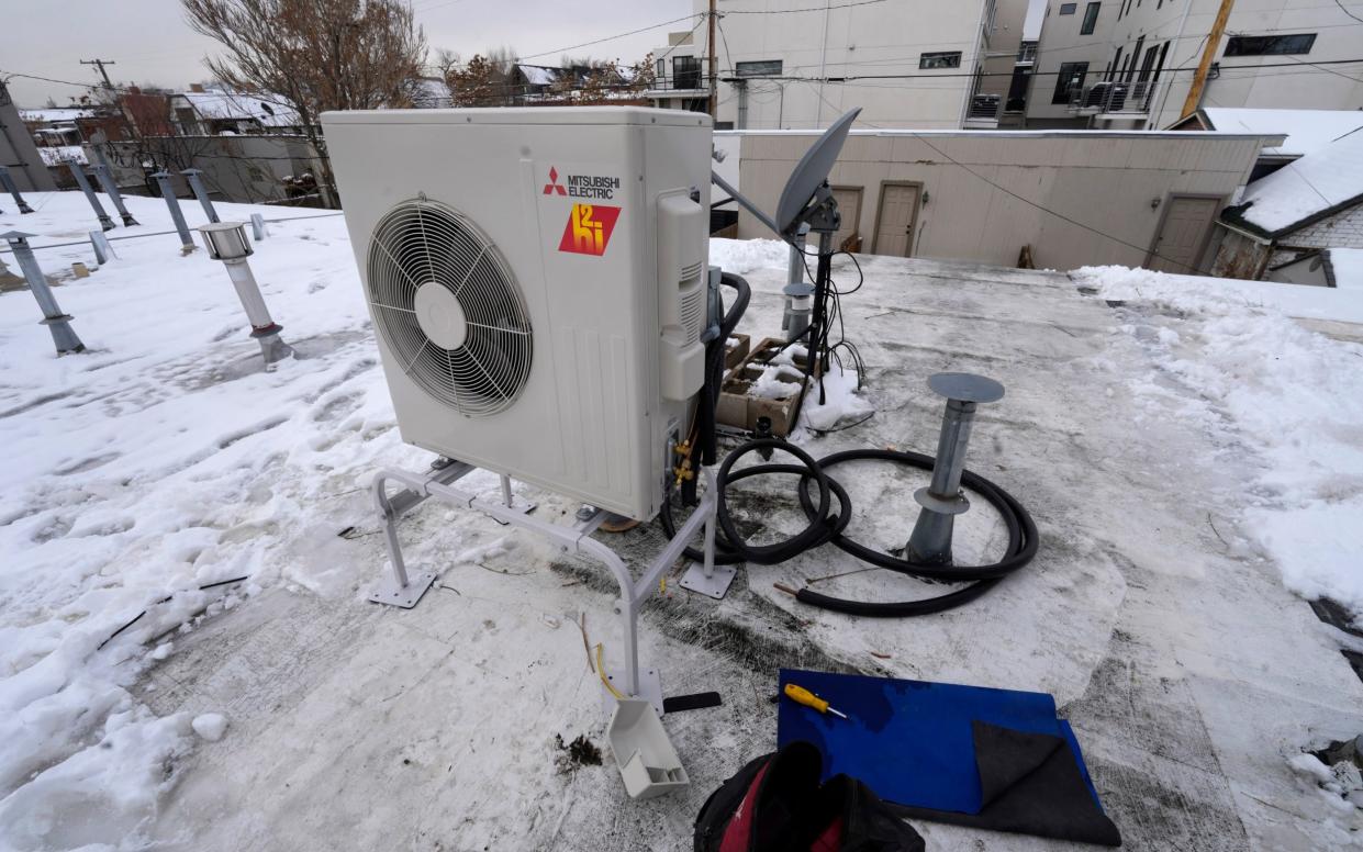 A condenser sits on the roof during the installation of a heat pump