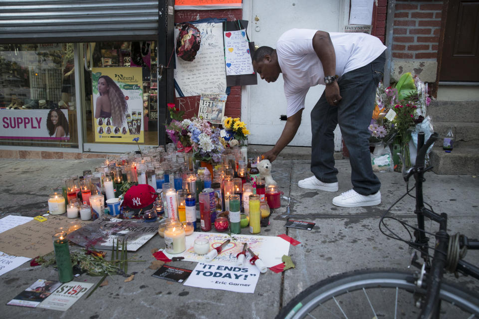 A mourner places a candle at a memorial for Eric Garner, a Staten Island man who died while being arrested by New York City police. (Photo: John Minchillo/AP)