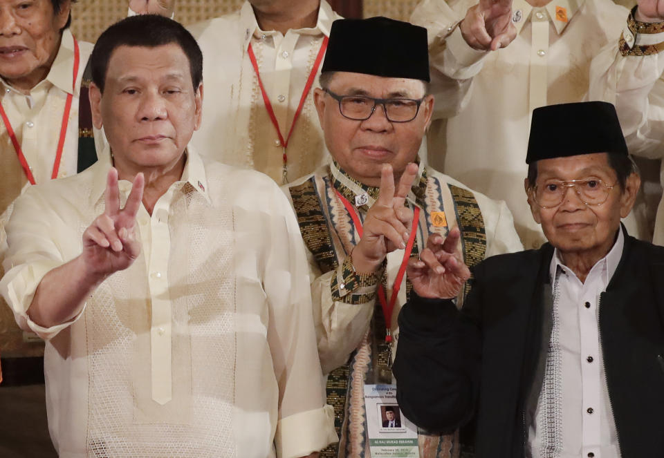 President Rodrigo Duterte, left, Murad Ebrahim, Chairman of the Moro Islamic Liberation Front, and Ghazali Jaafar, Vice-chair for Political Affairs and Chair of the Bangsamoro Transition Commission, flash the peace sign following oath-taking ceremony for the creation of the Bangsamoro Transition Authority or BTA at the Presidential Palace in Manila, Philippines Friday, Feb. 22, 2019. The Muslim rebels will serve as administrators of a new Muslim autonomous region in a delicate milestone to settle one of Asia's longest-raging rebellions. Several commanders, including Commander Bravo, long wanted for deadly attacks were given safety passes to be able to travel to Manila and join the ceremony. (AP Photo/Bullit Marquez)