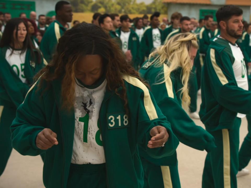 Players in green jumpsuit playing Red Light, Green Light