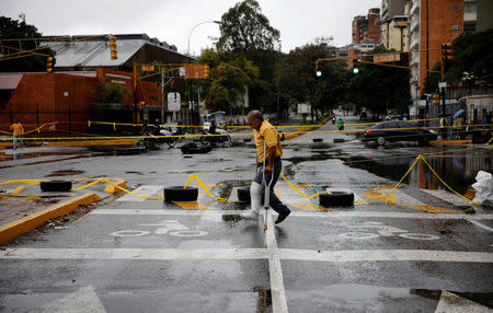 A pedestrian walks past a barricade during a rally against Venezuelan President Nicolas Maduro's government in Caracas, Venezuela, July 19, 2017. REUTERS/Carlos Garcia Rawlins