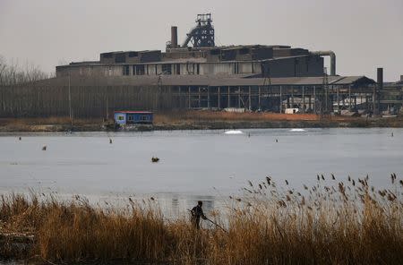 A man attempts to catch fish at a partially frozen fish farm near an abandoned steel mill of Qingquan Steel Group in Qianying township, Hebei province in this February 18, 2014 file photo. REUTERS/Petar Kujundzic/Files