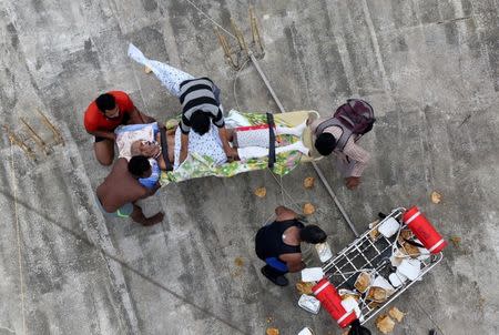 A sick man waits to be airlifted by the Indian Navy soldiers from a flooded area in Kerala, August 17, 2018. REUTERS/Sivaram V