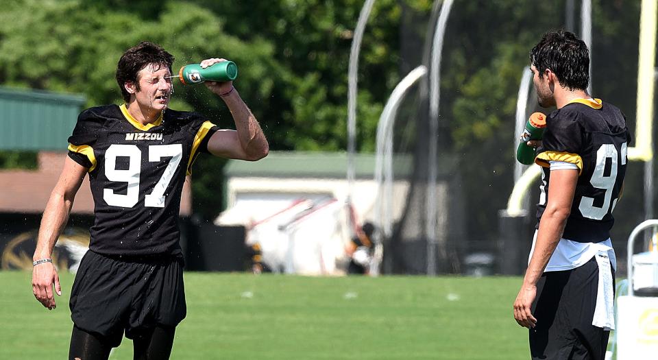 Missouri players Jack Stonehouse (97) and Luke Bauer, right, cool off during a break Aug. 1 during the Tigers' first fall practice.