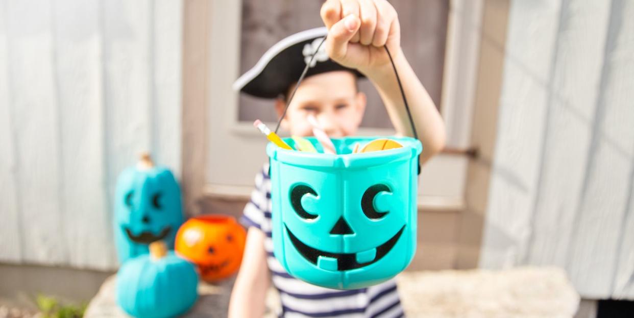 boy in a pirate costume holds a bucket with allergyfriendly halloween treats