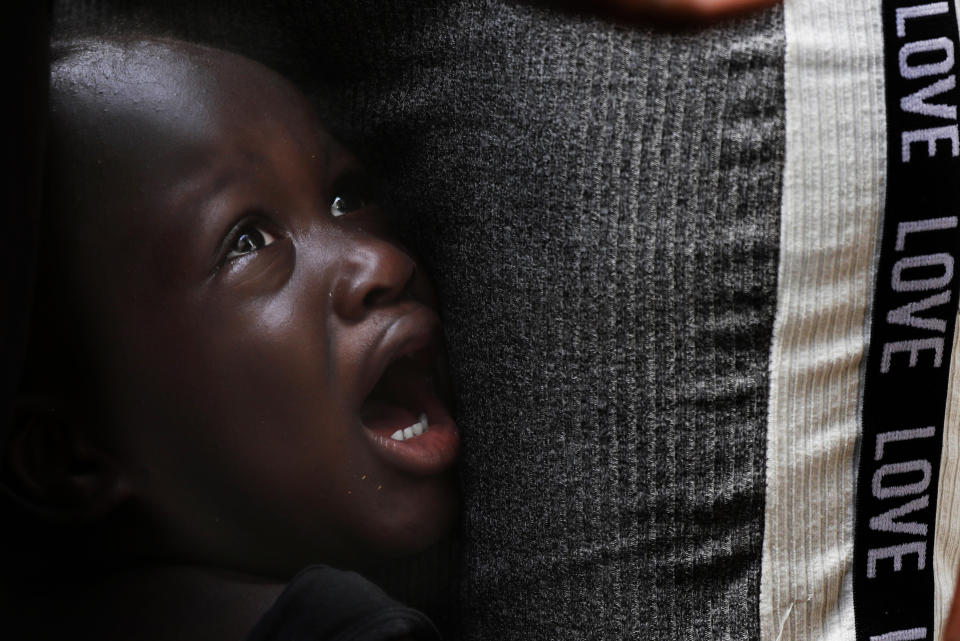 A Haitian migrant youth cries next to his father as they wait in line at an immigration center in Tapachula, Chiapas state, Mexico, Tuesday, May 28, 2019. The Mexican government is trying to encourage more migrants to regularize their status and stay in the south, but for most the United States remains the goal. (AP Photo/Marco Ugarte)