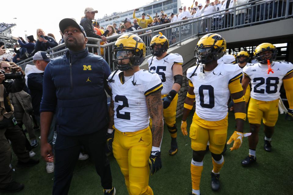 Wolverines offensive line coach Sherrone Moore leads the team onto the field before a game against the Nittany Lions.