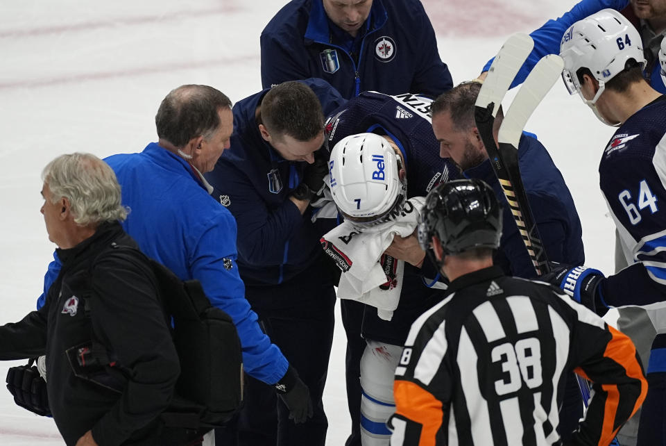 Trainers attend to Winnipeg Jets center Vladislav Namestnikov after he was hit in the face by a slap shot in the third period of Game 4 of an NHL Stanley Cup first-round playoff series against the Colorado Avalanche, Sunday, April 28, 2024, in Denver. (AP Photo/David Zalubowski)