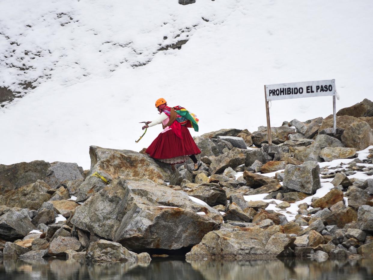 A mountain guide in the Cholita climbers group passes in front of a no trespassing sign