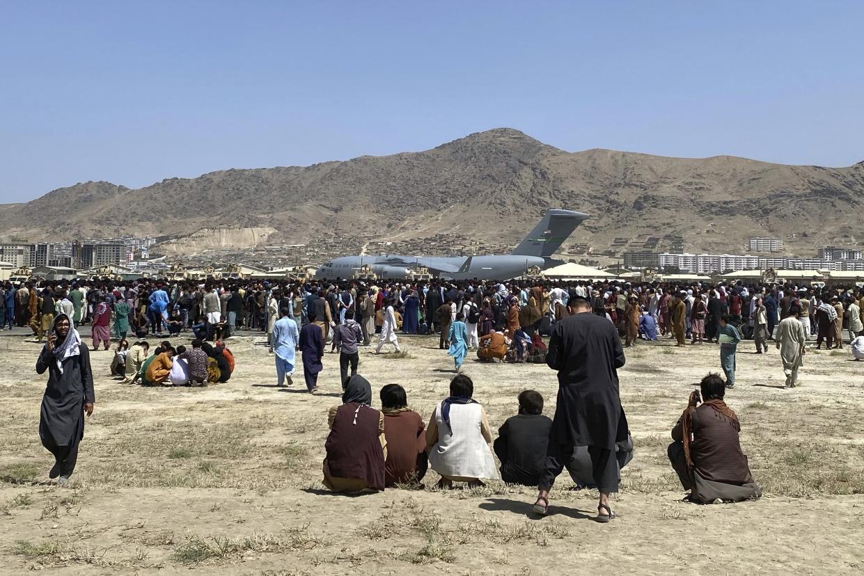 Hundreds of people gather near a U.S. Air Force C-17 transport plane at a perimeter at the international airport in Kabul, Afghanistan on Monday, Aug. 16, 2021. On Monday, the U.S. military and official's focus was on Kabul’s airport, where thousands of Afghans trapped by the sudden Taliban takeover rushed the tarmac and clung to U.S. military planes deployed to fly out staffers of the U.S. Embassy, which shut down Sunday, and others.