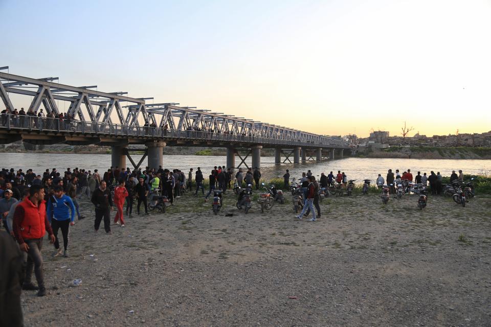 People and relatives of victims waiting on the bank of the Tigris river where the ferry sank in Mosul, Iraq, Thursday, March 21, 2019. A ferry overloaded with people celebrating the Kurdish new year sank in the Tigris River near the Iraqi city of Mosul on Thursday, killing dozens of people, mostly women and children, officials said. (AP Photo/Farid Abdulwahed)