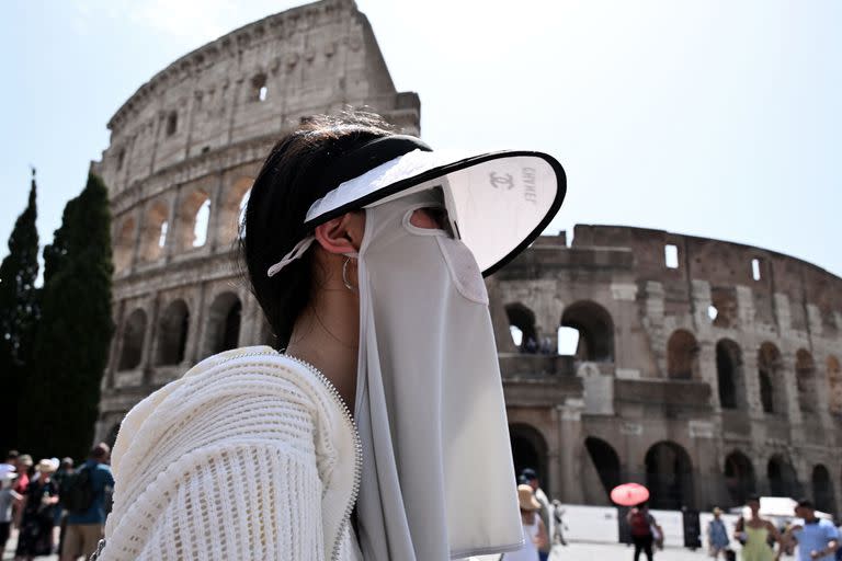 Un turista se protege del sol con ropa de protección solar mientras camina frente al monumento del Coliseo en Roma, el 24 de julio de 2023, durante una ola de calor en Italia.