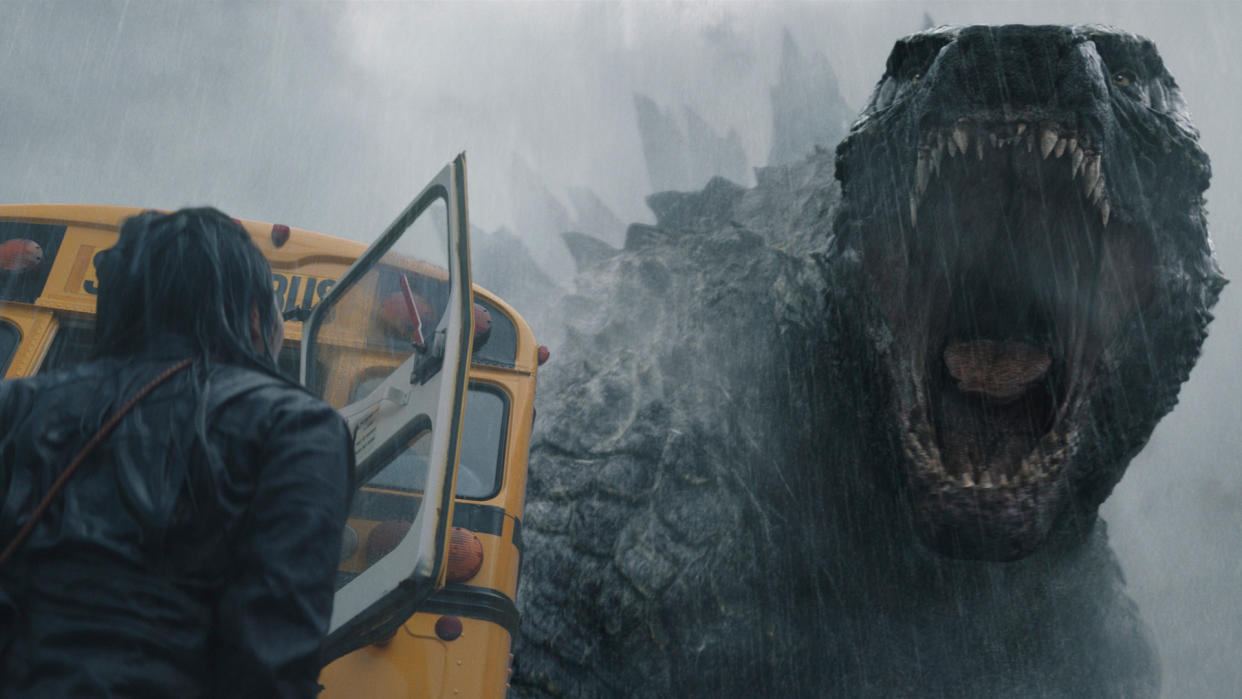  Godzilla roars at a person who's standing next to a school bus in Monarch: Legacy of Monsters 