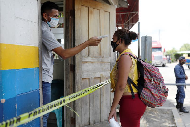 A man checks the temperature of a migrant from Honduras who was trying to reach the U.S., at the Corinto border between Guatemala and Honduras, in Puerto Barrios