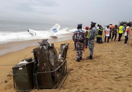 Policemen and rescuers stand near the wreckage of a propeller-engine cargo plane after it crashed in the sea near the international airport in Ivory Coast's main city, Abidjan, October 14, 2017. REUTERS/Luc Gnago