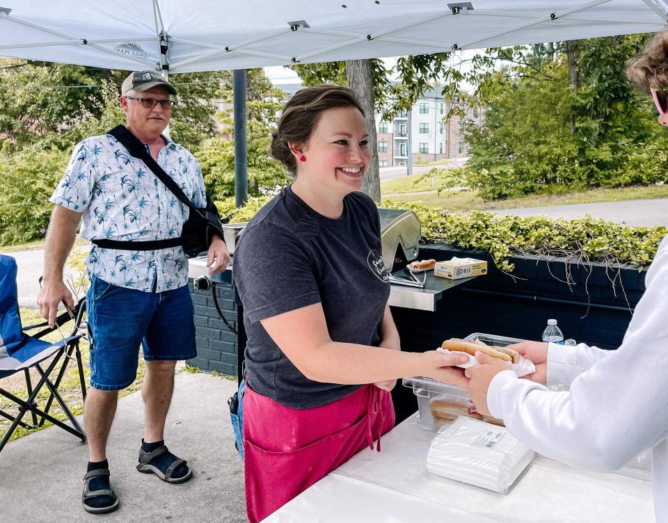 Staci Meyer, co-owner of The Sugar Queen Creamery, and her father, Merlin Gingerich, grill and hand out free hot dogs to customers to celebrate the ice cream shop’s first year on June 29, 2023.