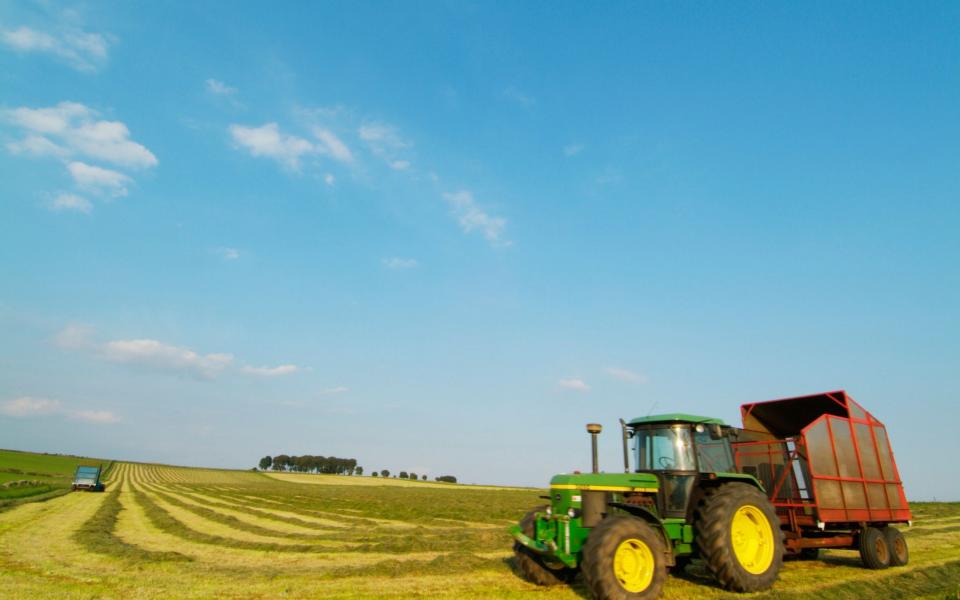 A tractor in a harvested field on a sunny day - Credit: eye35/Alamy