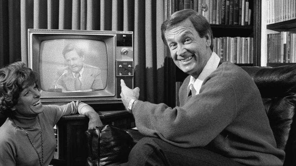 American game show host Bob Barker points to himself on a nearby television screen as his wife Dorothy Jo Barker (1924 - 1981) looks on and laughs, November 4, 1977.  - CBS/Getty Images