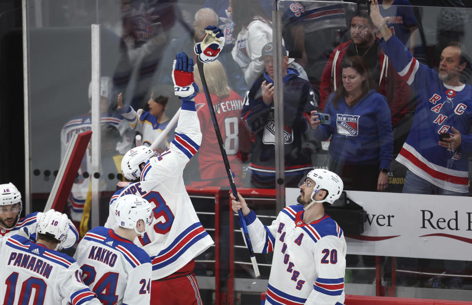 New York Rangers left wing Chris Kreider (20) holds his glove on a stick to high-five teammate Matt Rempe after defeating the Washington Capitals in Game 3 of an NHL hockey Stanley Cup first-round playoff series, Friday, April 26, 2024, in Washington. (AP Photo/Tom Brenner)