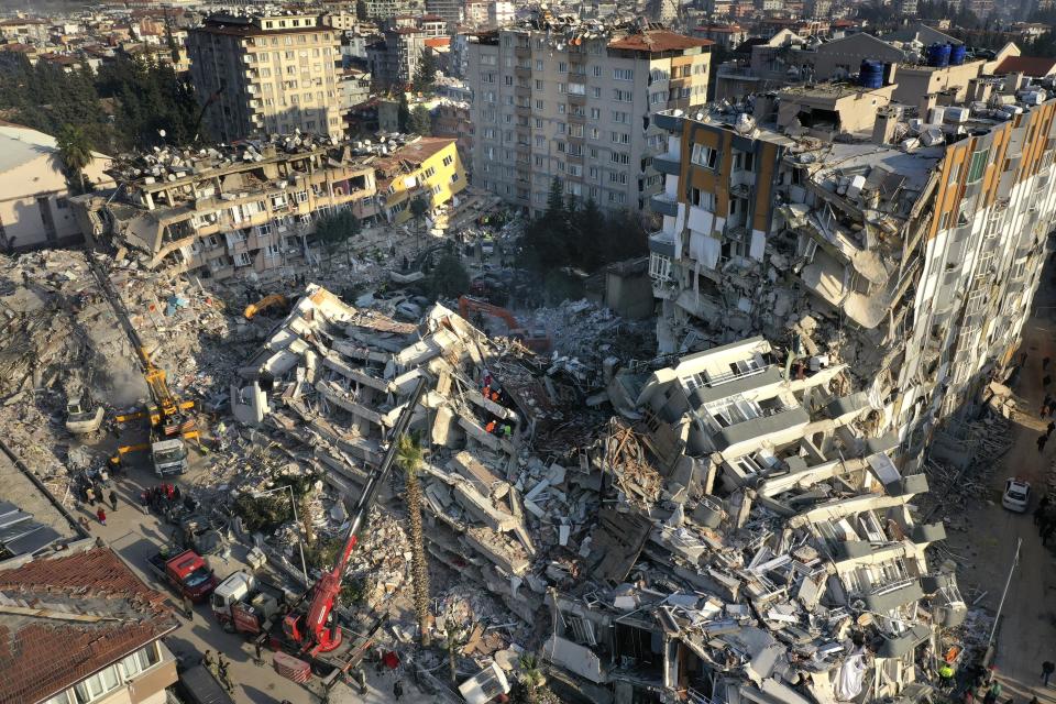 Rescue teams search for people as cranes remove debris from destroyed buildings in Antakya, southeastern Turkey, Friday, Feb. 10, 2023. Rescuers pulled several earthquake survivors from the shattered remnants of buildings Friday, including some who lasted more than 100 hours trapped under crushed concrete after the disaster slammed Turkey and Syria. (AP Photo/Hussein Malla)