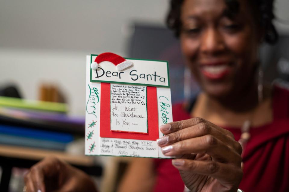 Alina Johnson, the owner of Johnson Consulting Services, shows a handmade holiday greeting card she made for her best friend that incorporated lyrics from her friend's favorite Christmas song by Mariah Carey that she wrote in calligraphy at a workstation in the bedroom of her home in Detroit on Dec. 13, 2022. Johnson sometimes carves out substantial time to make the cards where she incorporates calligraphy and origami envelopes and also sells her creations to Detroiters and other local people who care enough to give cards that make a personal, heartfelt statement during the holiday season.