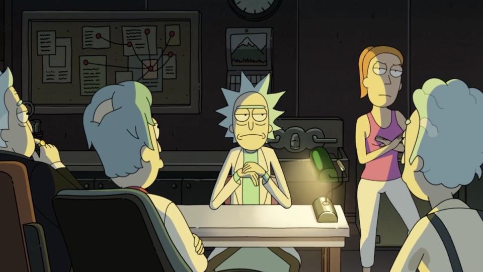 Rick sits at a desk with Summer stan ding on his right in front of other versions of himself