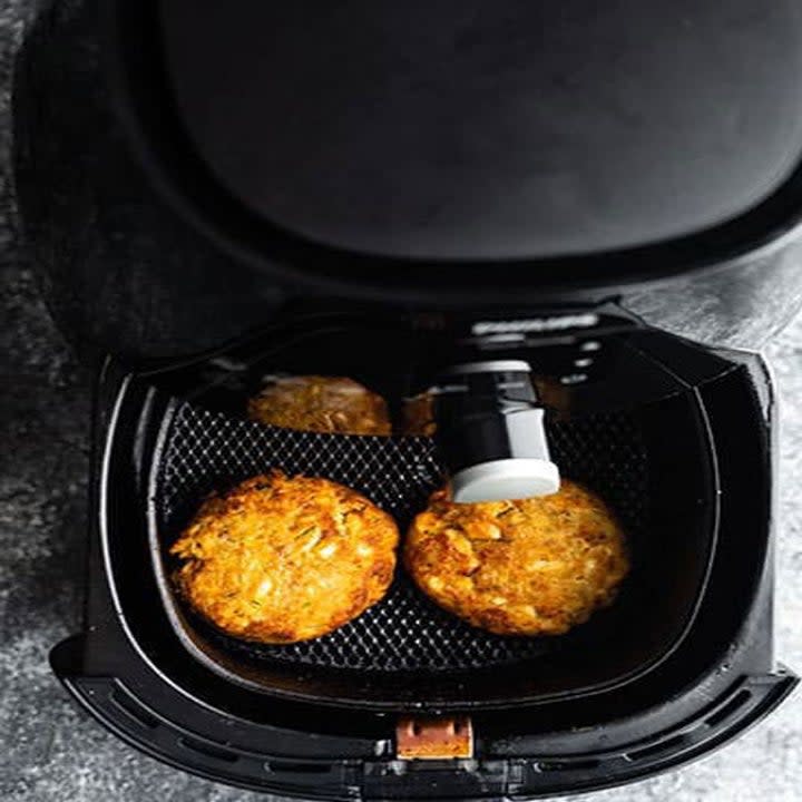 Two salmon patties in an air fryer basket.