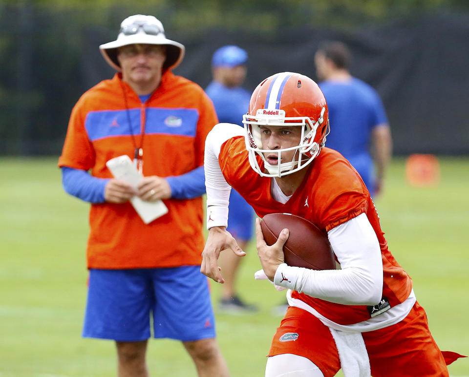 Florida quarterback Feleipe Franks (13) runs with the ball as head coach Dan Mullen watches during an NCAA college football practice in Gainesville, Fla., Friday, July 26, 2019. (Brad McClenny/The Gainesville Sun via AP)