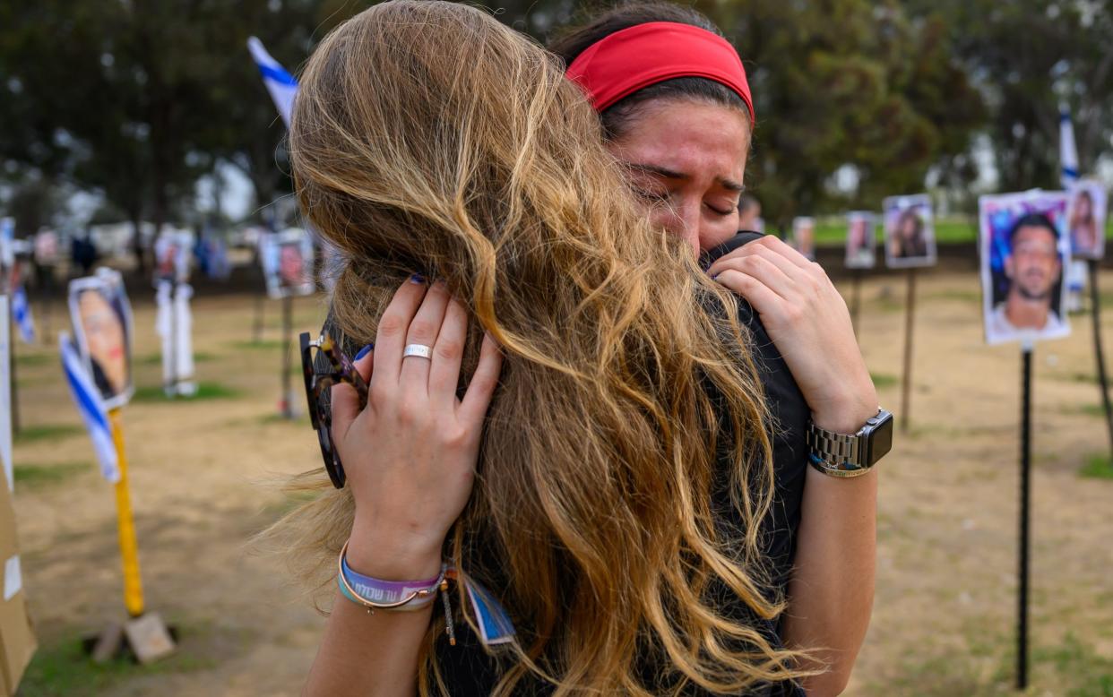 Atara, from London, hugs a friend and reacts while visiting a memorial displayed photos of people killed or kidnapped during the Hamas attack