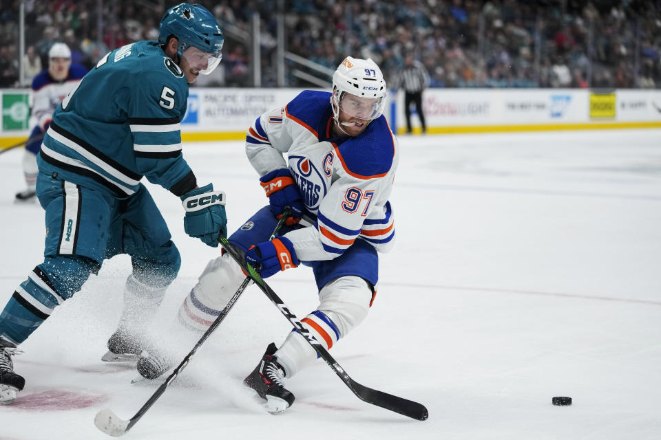 Edmonton Oilers center Connor McDavid (97) takes the puck away from San Jose Sharks defenseman Matt Benning during the second period of an NHL hockey game in San Jose, Calif., Friday, Jan. 13, 2023. (AP Photo/Godofredo A. Vásquez)