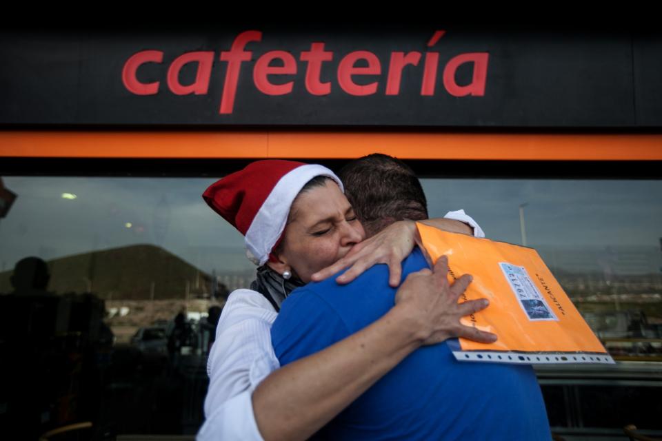 Gas station worker, Maria Gonzalez Jimenez, hugs a colleague after winning the second prize of the Christmas lottery “El Gordo” (“The Fat One”) in Santa Cruz de Tenerife in the Canary Islands, Spain, Sunday Dec. 22, 2013. Millions of Spaniards are glued to televisions as the country's cherished Christmas lottery, the world's richest, distributes a bounty of 2.5 billion euros ($3.4 billion) in prize money to winning ticket owners. The draw is so popular that most of Spain's 46 million inhabitants traditionally watch some part of it live in the hope that the school children singing out winning numbers will call out their ticket. The top prize, known as "El Gordo" (The Fat One), gives lucky winners 400,000 euros per ticket Sunday, while the second-best number nets 125,000 euros. (AP Photo/Andres Gutierrez)