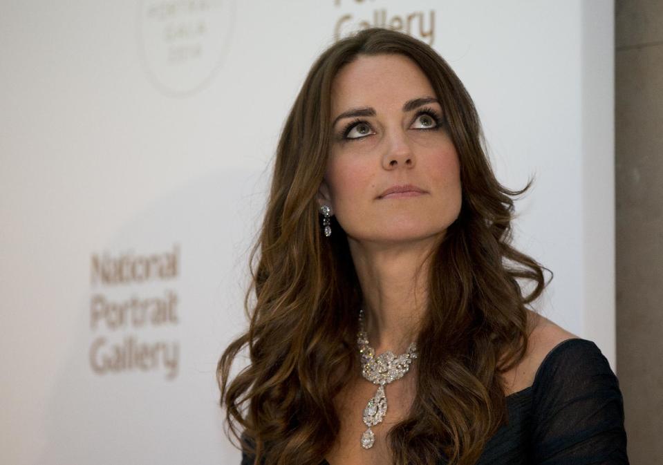 Kate Duchess of Cambridge waits to make a few remarks at a fund raising gala at the National Portrait Gallery in London, Tuesday, Feb. 11, 2014. . The Duchess is wearing a dress by British designer Jenny Packham and a necklace on loan from Queen Elizabeth II that was given to the Queen as a gift for her wedding in 1947. (AP Photo/Alastair Grant, Pool)