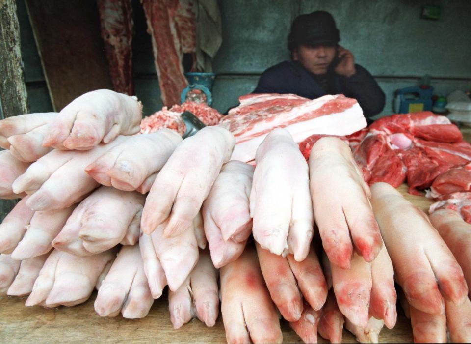 A meat vendor sits behind a pile of pigs feet for sale in central Beijing.&nbsp; (Photo: Reuters Photographer/Reuters)