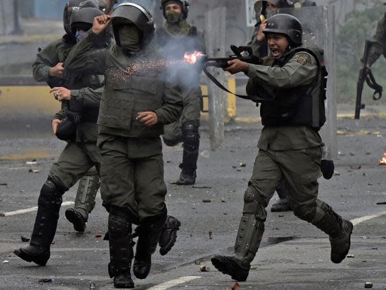 A member of the national guard fires a shotgun at opposition demonstrators during clashes in Caracas last year (AFP/Getty)