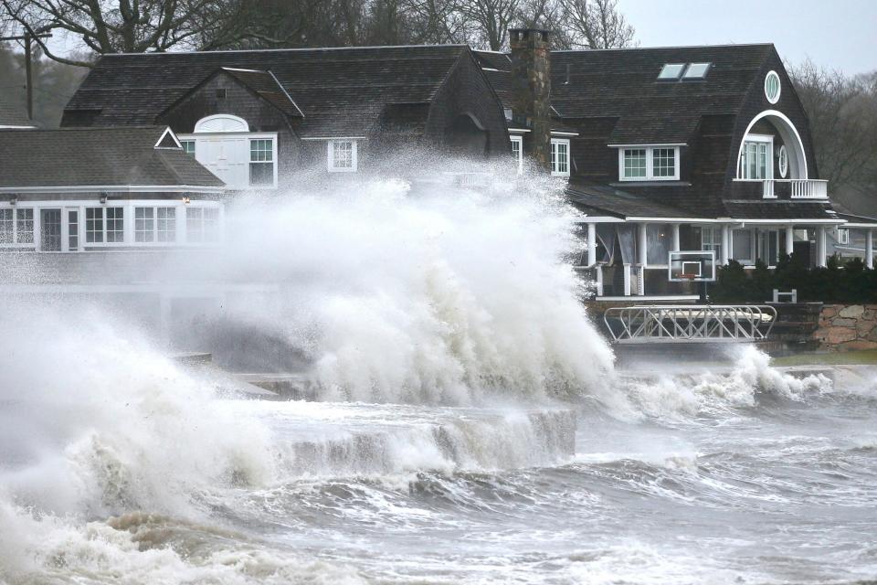 High winds drive surf into a retaining wall in front of a residence in Mattapoisett, Mass (AP)