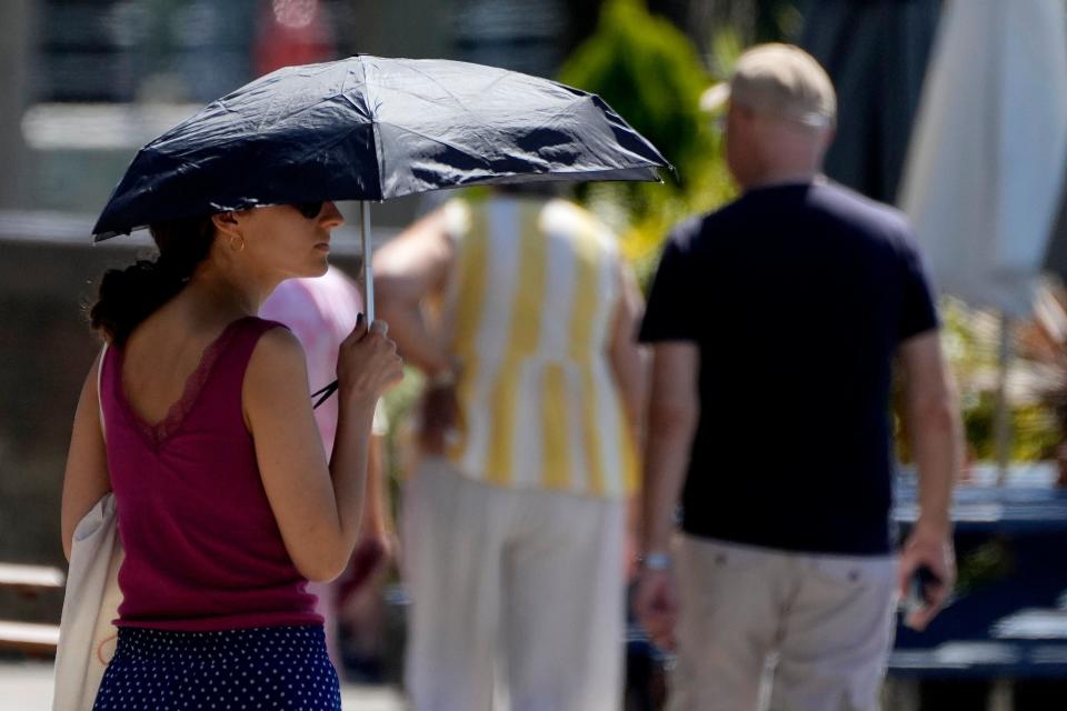 A woman uses an umbrella to shelter from the sun near Hammersmith, London (Frank Augstein/AP)