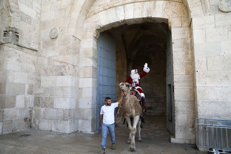 Israeli-Arab Issa Kassissieh rides a camel wearing a Santa Claus costume during the annual Christmas tree distribution by the Jerusalem municipality in Jerusalem's Old City December 21, 2017. REUTERS/Ammar Awad