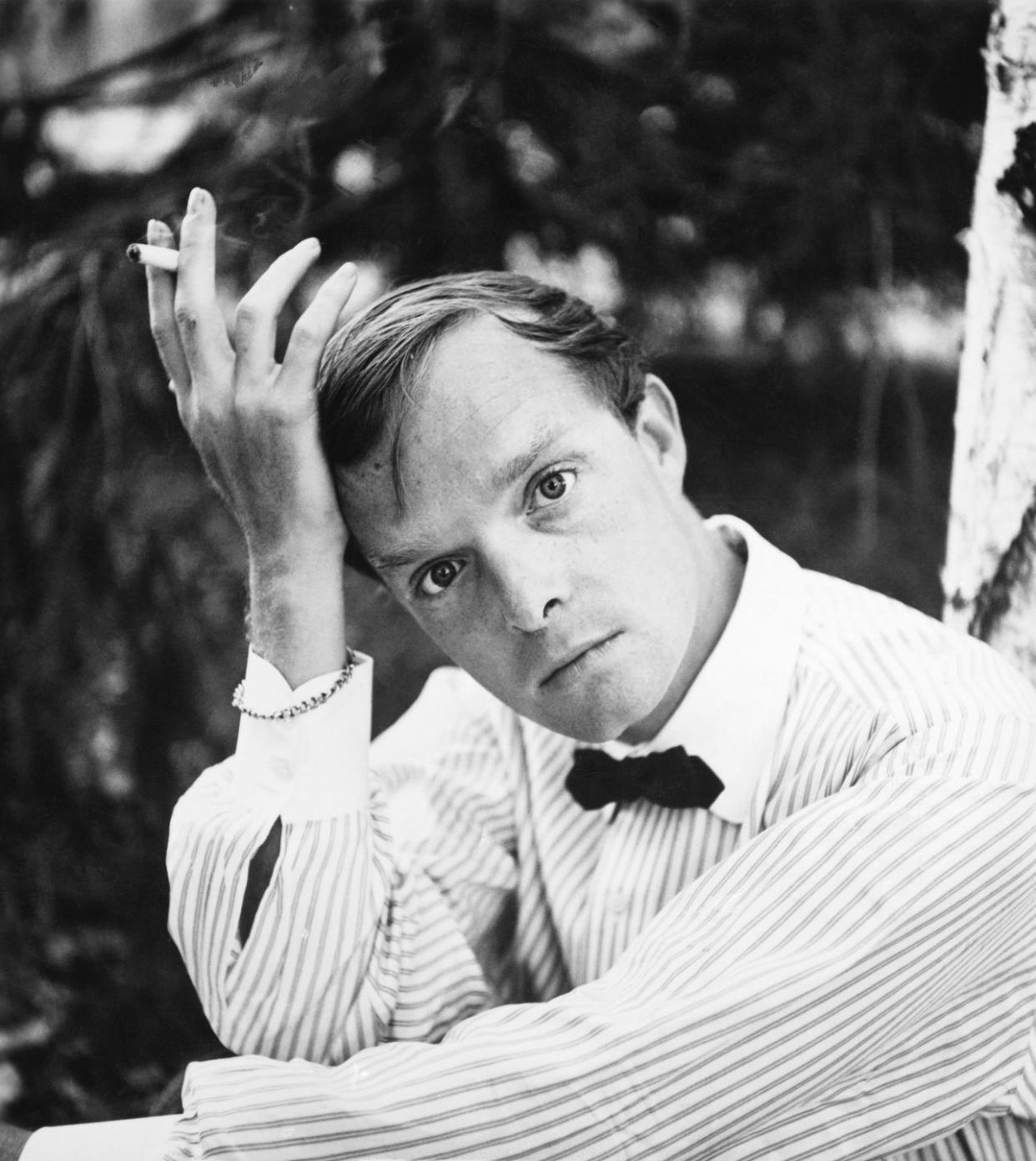 author truman capote posing outdoors with cigarette