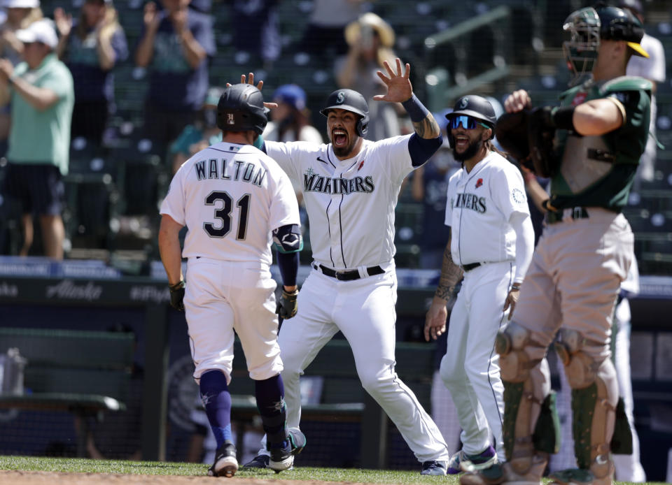 Seattle Mariners' Jacob Nottingham, center, and J.P. Crawford, right, greet Donovan Walton at home after he hit a three-run home run during the fourth inning of a baseball game, Monday, May 31, 2021, in Seattle. (AP Photo/John Froschauer)