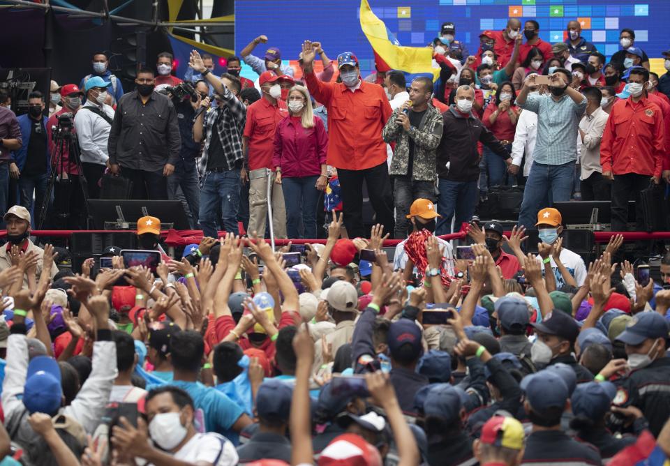Venezuela's President Nicolas Maduro, center, and first lady Cilia Flores who is also a candidate for the National Assembly, wave at supporters during a closing campaign rally for the upcoming National Assembly elections in Caracas, Venezuela, Thursday, Dec. 3, 2020. Venezuelans will vote for a new National Assembly this Sunday, Dec 6. (AP Photo/Ariana Cubillos)