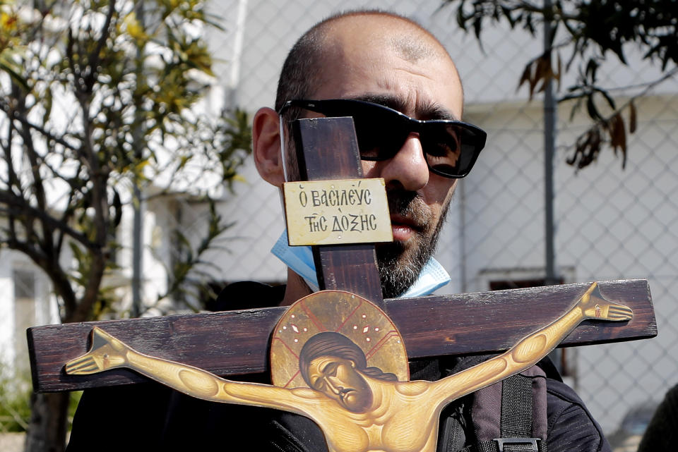 A protestor holds a cross, outside Cyprus' national broadcasting building, during a protest, in capital Nicosia, Cyprus, Saturday, March 6, 2021. The Orthodox Church of Cyprus is calling for the withdrawal of the country’s controversial entry into this year’s Eurovision song context titled “El Diablo”, charging that the song makes an international mockery of country’s moral foundations by advocating “our surrender to the devil and promoting his worship.” (AP Photo/Petros Karadjias)