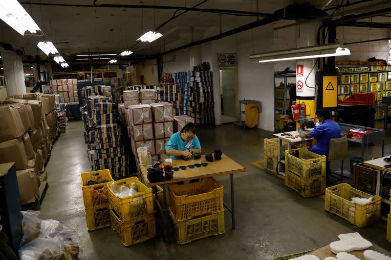 Un trabajador pone pegamento en las suelas de la fábrica de calzado Full Time, en Caracas