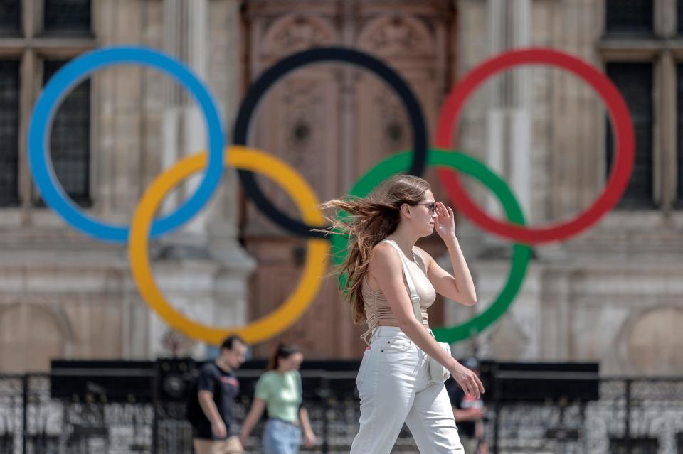 A woman passes by the Olympic rings at City Hall in Paris.